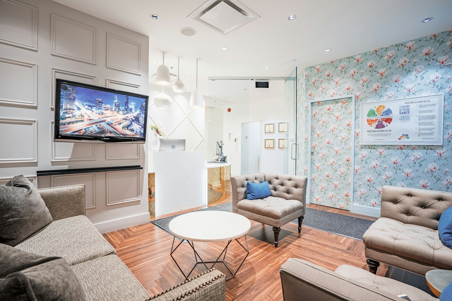 Modern waiting area with sofas, a reception desk, and floral wallpaper.