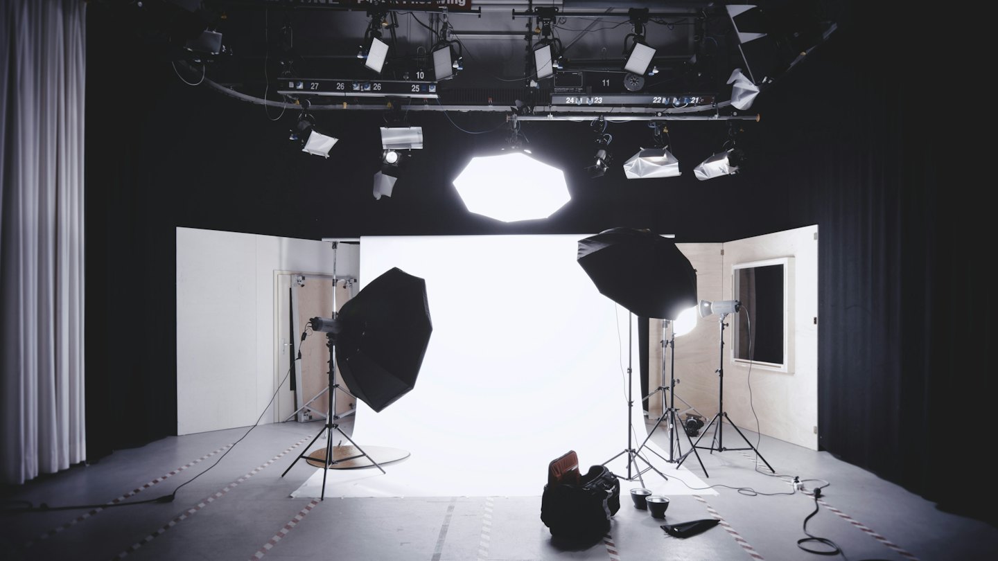 Brightly lit photo studio with seamless white backdrop and lighting equipment.