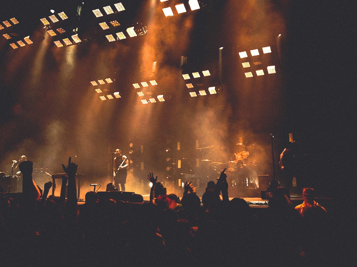 Band performs on a smoke-filled stage under orange spotlights.