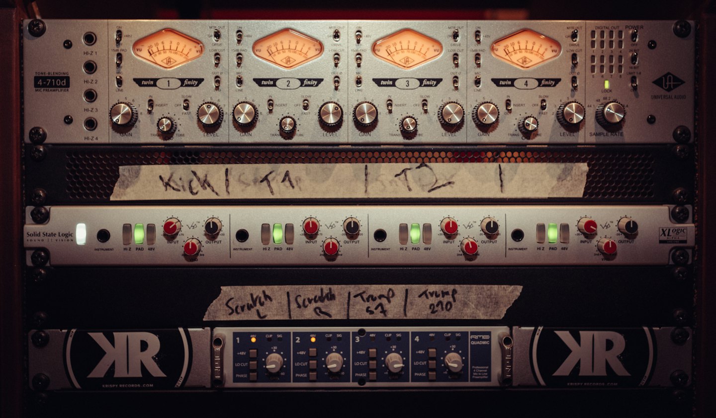 Audio rack gear with handwritten labels in a recording studio.