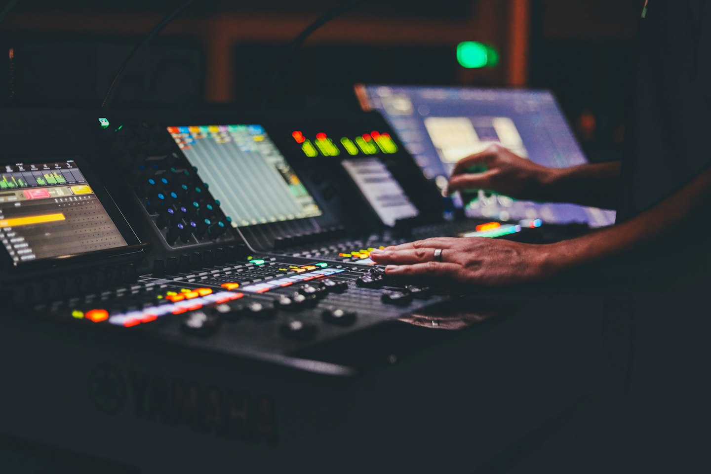 Audio engineer adjusts faders on a sound mixing console.